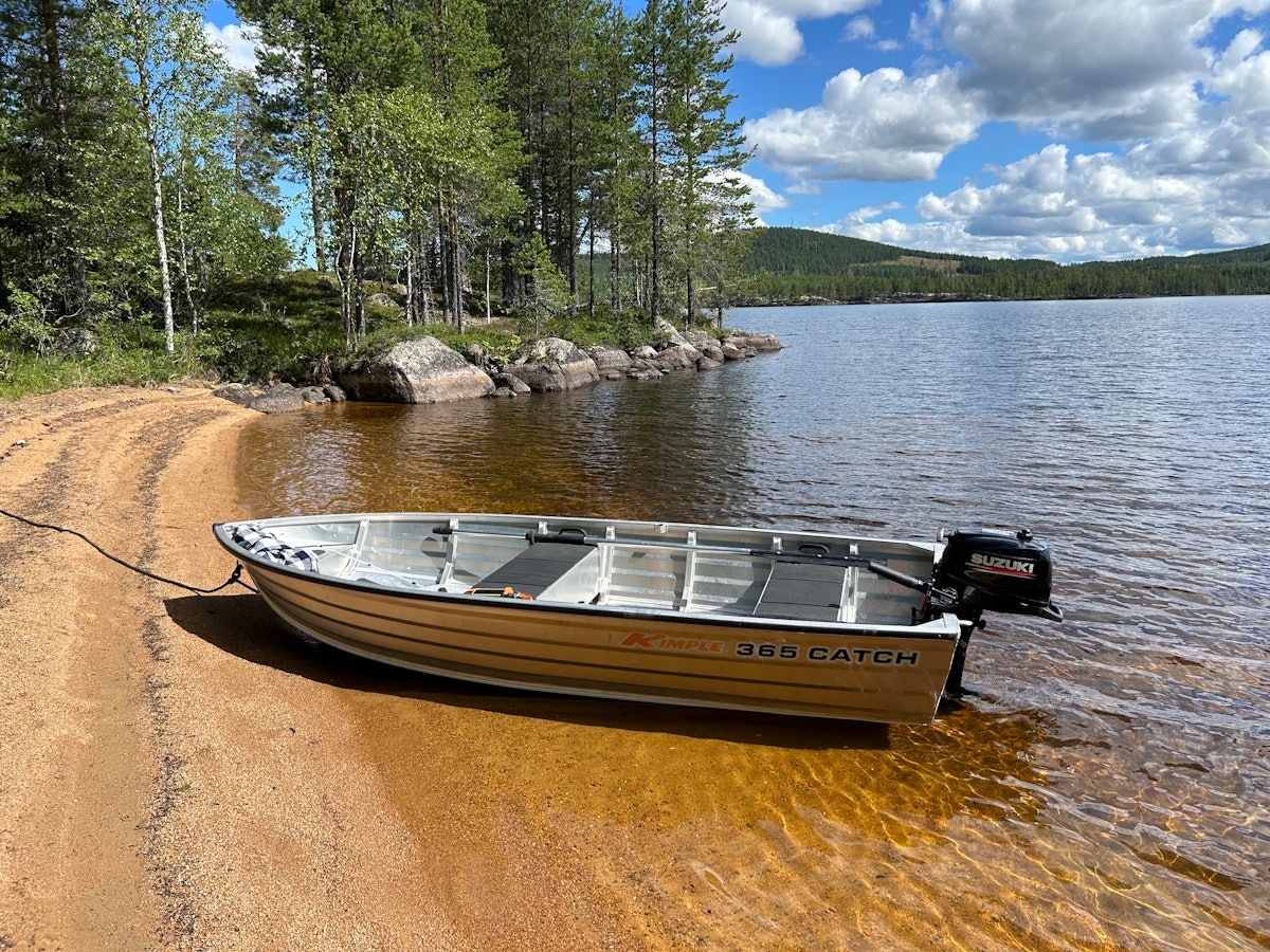 Aluminiumbåt med motor vid strandkant.